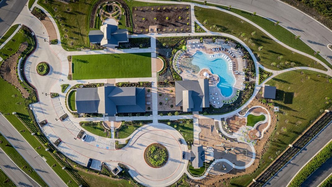 An aerial perspective showcases a vibrant community recreation area with a winding pool, playground, and manicured green spaces.