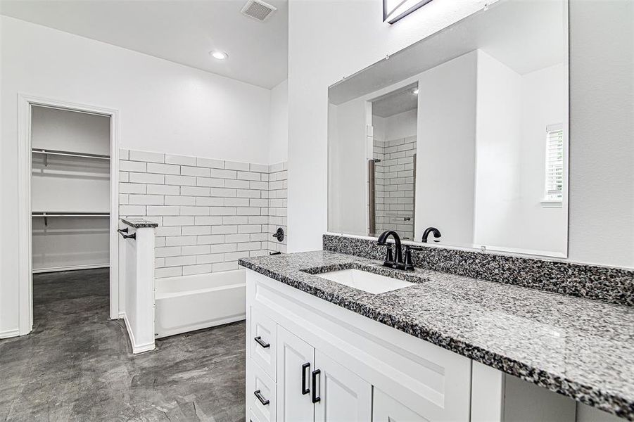 Bathroom with tiled shower / bath combo, vanity, and tile patterned floors