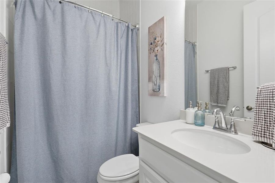 Bathroom featuring a single vanity with an integrated sink, polished chrome faucet, and a large mirror Bathroom featuring a single vanity with an integrated sink, polished chrome faucet, and a large mirror