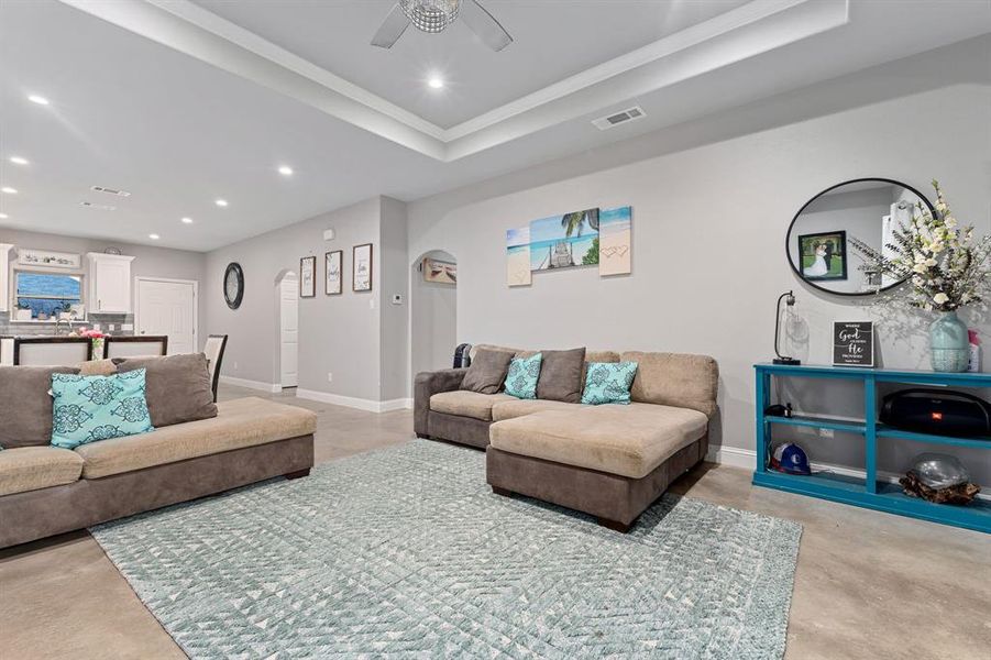 Living room with a tray ceiling and ceiling fan