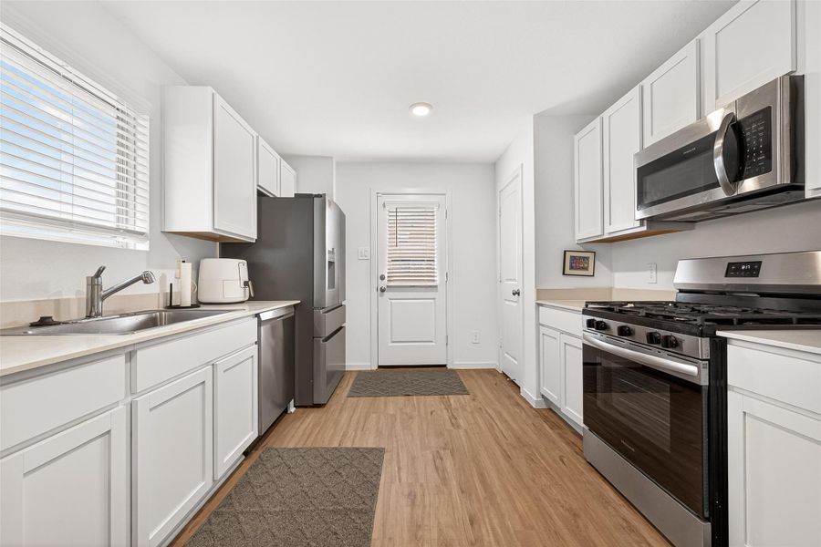 The galley-style design features sleek white cabinetry and coordinated stainless steel appliances. The galley-style design features sleek white cabinetry and coordinated stainless steel appliances.