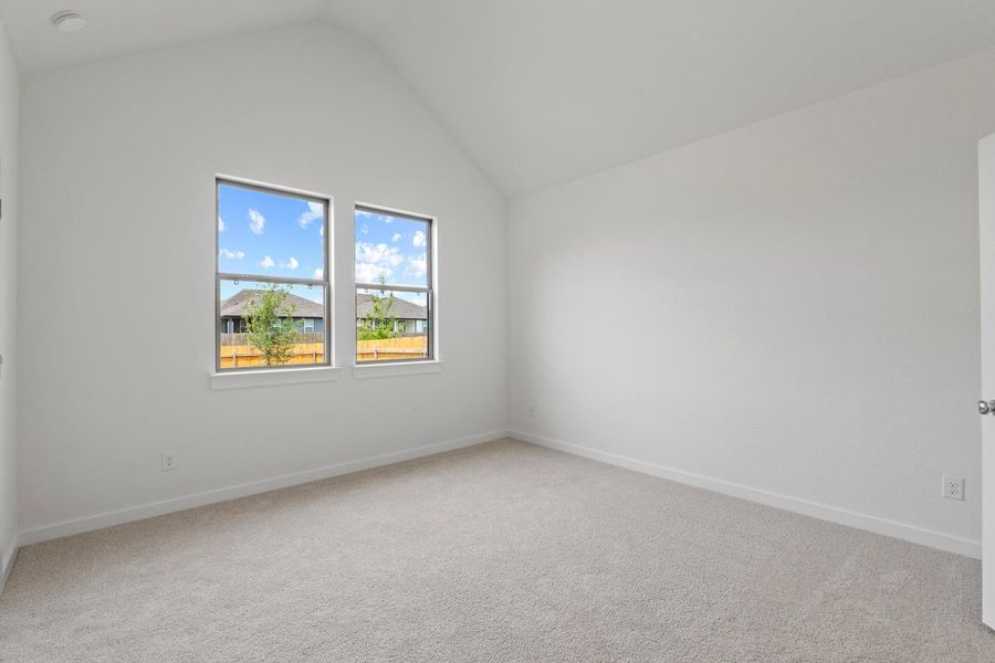 An airy bedroom with vaulted ceilings offers serene views through generous windows. An airy bedroom with vaulted ceilings offers serene views through generous windows.