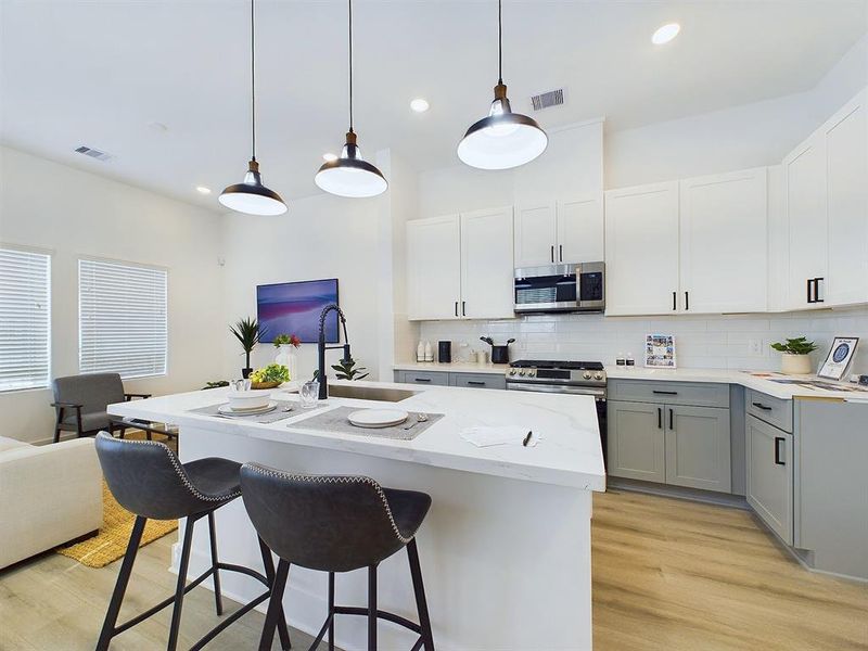 This attractive kitchen is full of beautiful details. Quartz countertops, stainless steel sink, stainless steel appliances, recessed lighting, undercabinet lighting, pantry, elegant cabinetry with soft close drawers and doors. Photos from another development by Disama Building Group. FINISHES & COLORS MAY VARY.