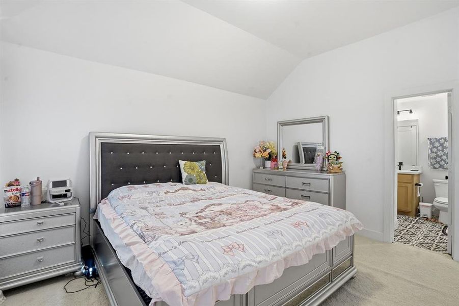 Bedroom with vaulted ceiling, light colored carpet, and ensuite bathroom Bedroom with vaulted ceiling, light colored carpet, and ensuite bathroom