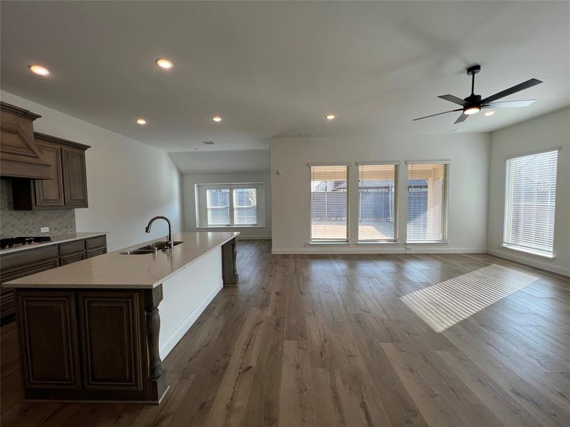 Kitchen featuring a center island with dual sink, open floor plan, dark wood-type flooring, a ceiling fan, quartz countertops, gas cooktop, and Arabesque tile backsplash Kitchen featuring a center island with dual sink, open floor plan, dark wood-type flooring, a ceiling fan, quartz countertops, gas cooktop, and Arabesque tile backsplash