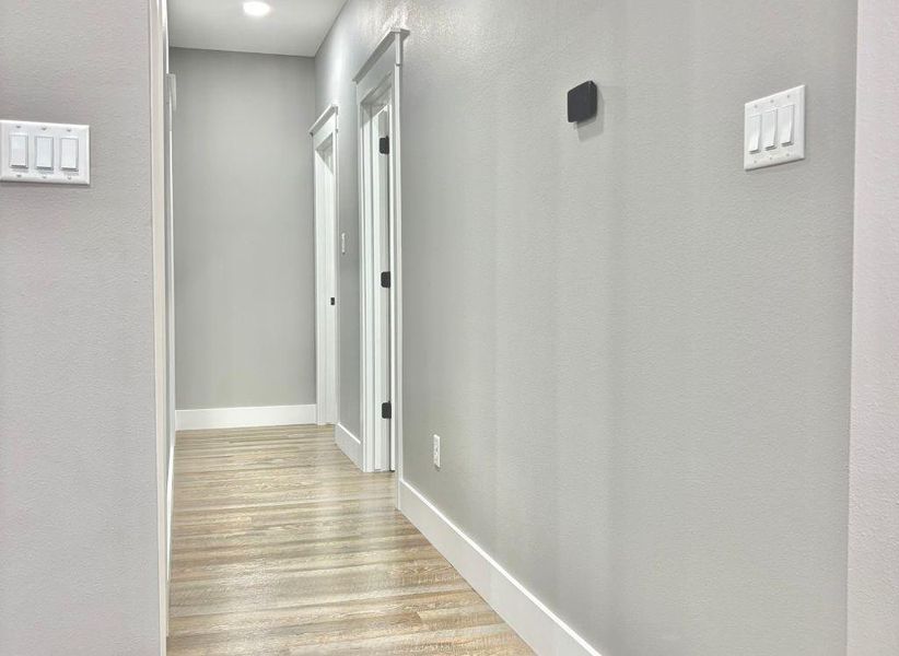 Hallway featuring light wood-type flooring and a textured wall Hallway featuring light wood-type flooring and a textured wall