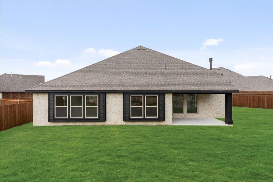 Rear exterior of single-story brick home with dark trim, large windows, covered patio, and fenced backyard Rear exterior of single-story brick home with dark trim, large windows, covered patio, and fenced backyard