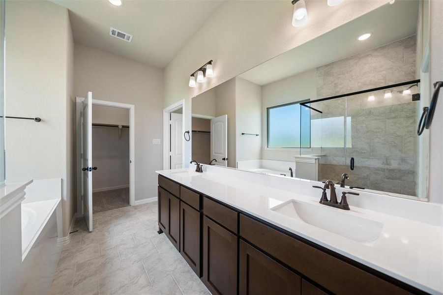 Full bath featuring a bath, a stall shower, double vanity, a walk in closet, and recessed lighting Full bath featuring a bath, a stall shower, double vanity, a walk in closet, and recessed lighting