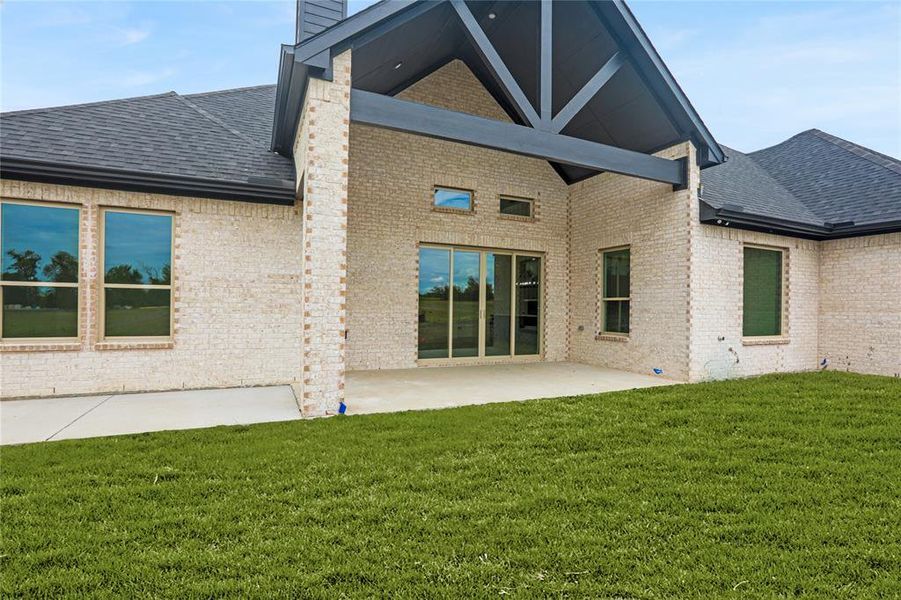 Back of house featuring roof with shingles, a patio, brick siding, and a chimney Back of house featuring roof with shingles, a patio, brick siding, and a chimney