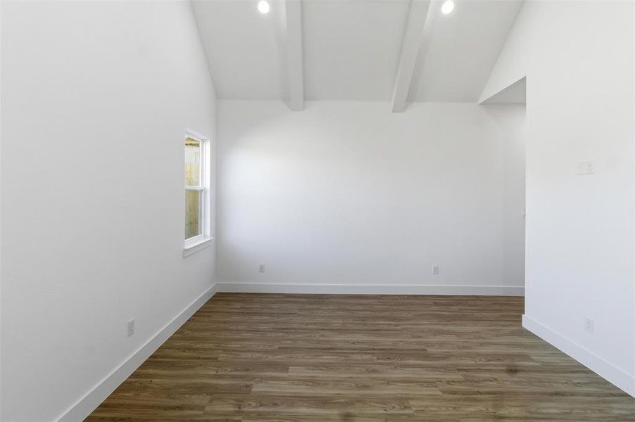 Unfurnished room with dark wood-style floors and lofted ceiling