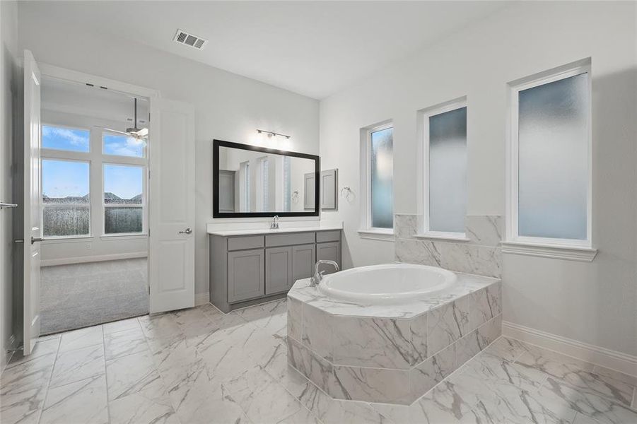 Full bathroom featuring baseboards, marble finish flooring, vanity, a garden tub, and ceiling fan
