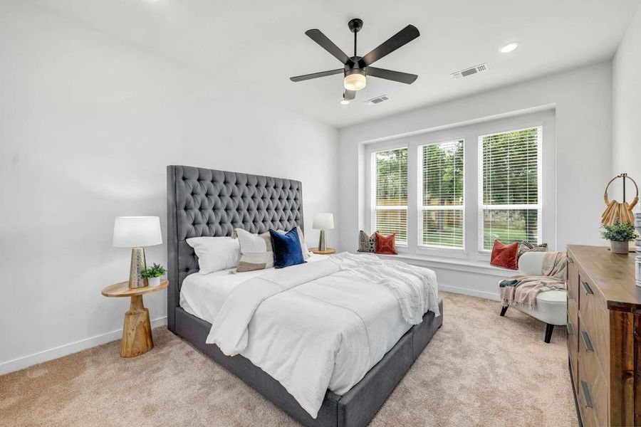 Carpeted bedroom featuring baseboards, visible vents, and a ceiling fan