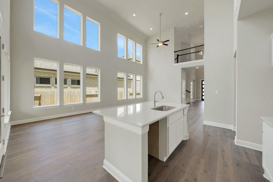 Kitchen featuring a ceiling fan, open floor plan, a high ceiling, dark wood finished floors, and white cabinets Kitchen featuring a ceiling fan, open floor plan, a high ceiling, dark wood finished floors, and white cabinets