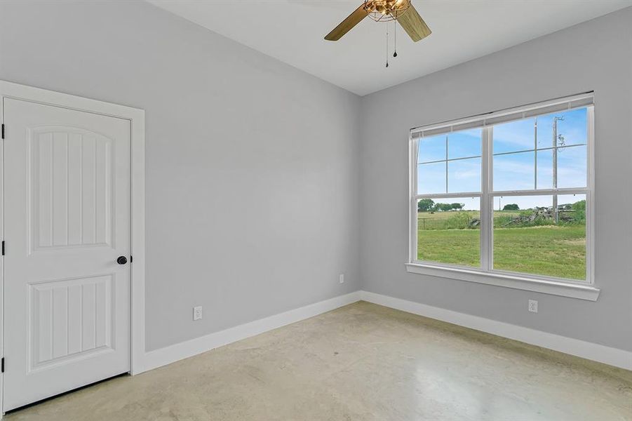 Unfurnished room with concrete floors, ceiling fan, and baseboards
