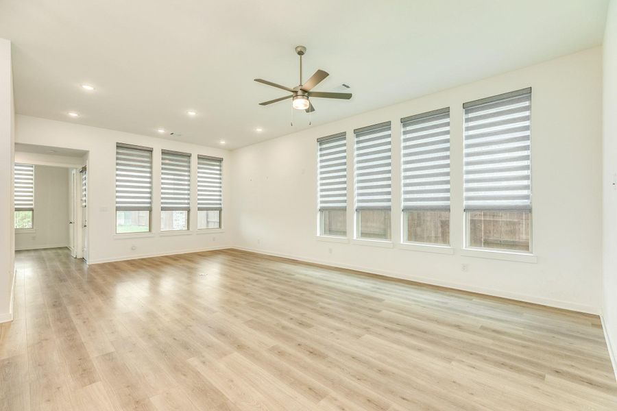 The spacious family room features beautiful, easy-to-maintain flooring and is bathed in natural light, thanks to the expansive windows lining the walls.