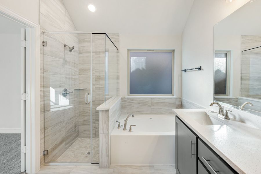 Master bathroom with glass walk-in shower, soaking tub, and double vanity with quartz countertop