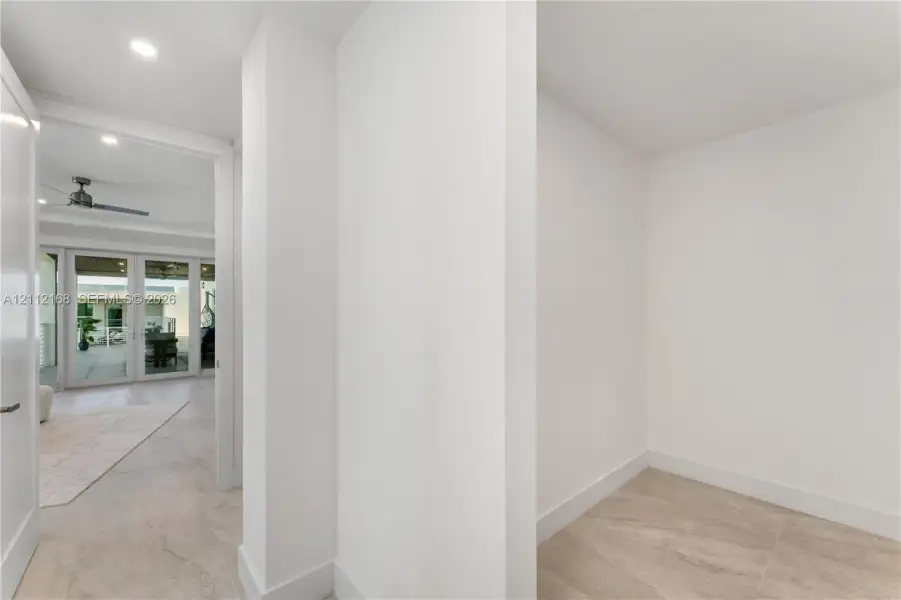 Neutral interior featuring smooth white wall finishes, recessed lighting, and stone-finish tile flooring Neutral interior featuring smooth white wall finishes, recessed lighting, and stone-finish tile flooring