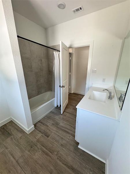 Full bath with shower / tub combo, vanity, and dark wood-style floors Full bath with shower / tub combo, vanity, and dark wood-style floors