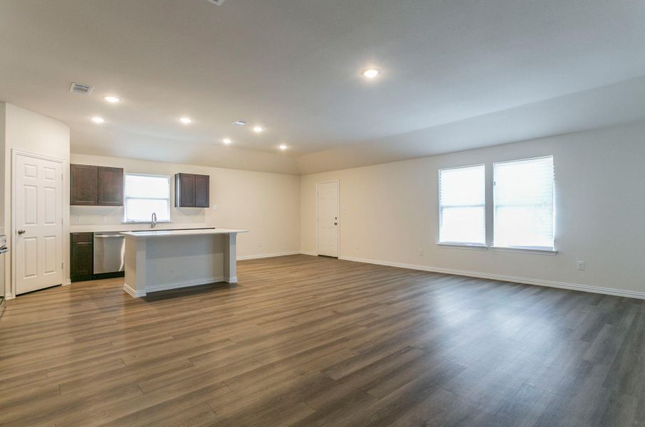 Kitchen with light countertops, stainless steel dishwasher, a kitchen island, open floor plan, and dark wood-style flooring