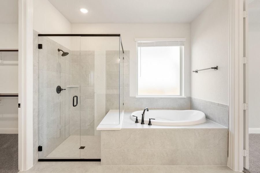 Master bathroom with soaking tub, glass-enclosed tile shower, and matte black fixtures