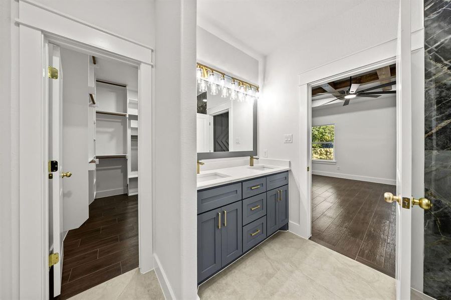 Full bath featuring wood tiled floors, double vanity, a walk in closet, and ceiling fan Full bath featuring wood tiled floors, double vanity, a walk in closet, and ceiling fan