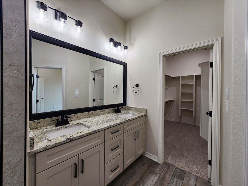 Bathroom vanity featuring dual sinks with granite countertops and matte black fixtures