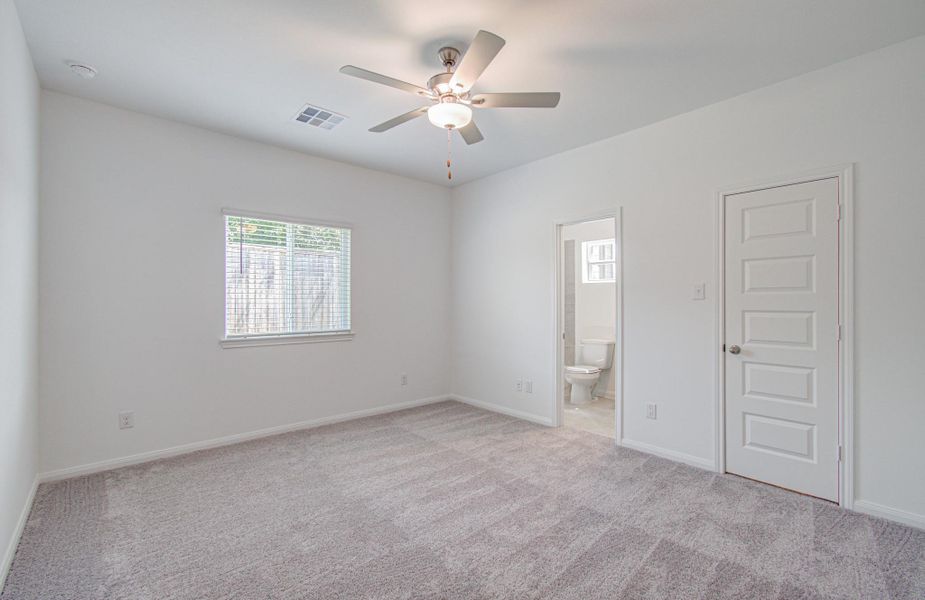 Spacious bedroom featuring plush carpeting, a ceiling fan, and a private en-suite bathroom for added convenience.