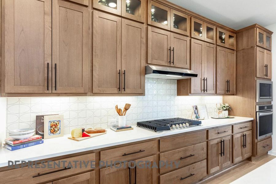 Kitchen featuring appliances with stainless steel finishes, under cabinet range hood, light countertops, and tasteful backsplash