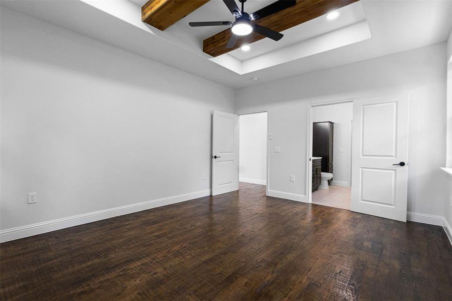Unfurnished bedroom with wood finished floors, ensuite bath, a tray ceiling, a ceiling fan, and recessed lighting Unfurnished bedroom with wood finished floors, ensuite bath, a tray ceiling, a ceiling fan, and recessed lighting