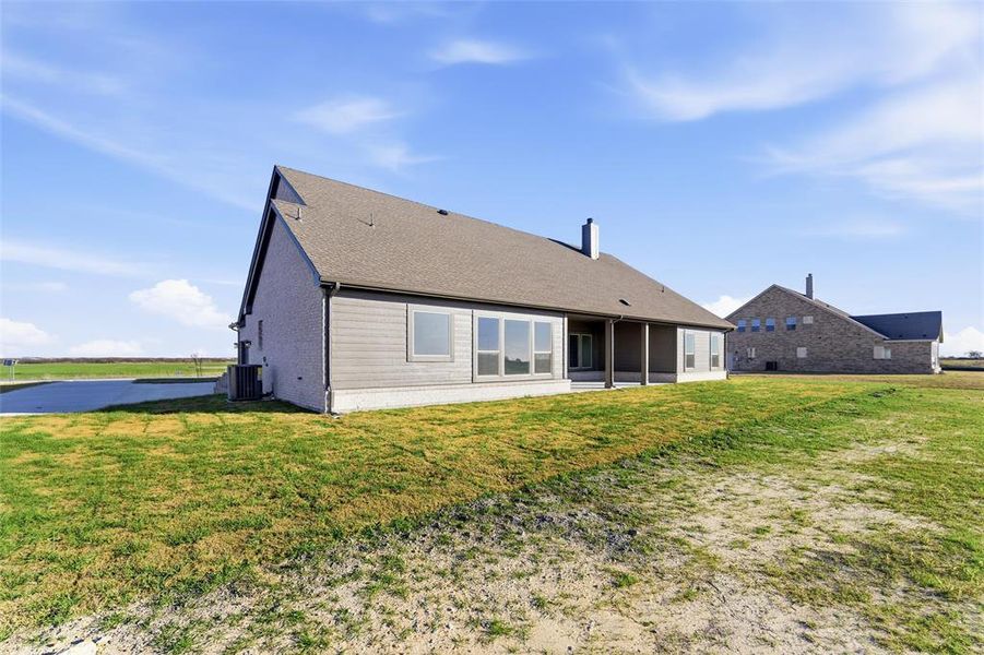 Back of property with a lawn, a patio area, brick siding, and a chimney