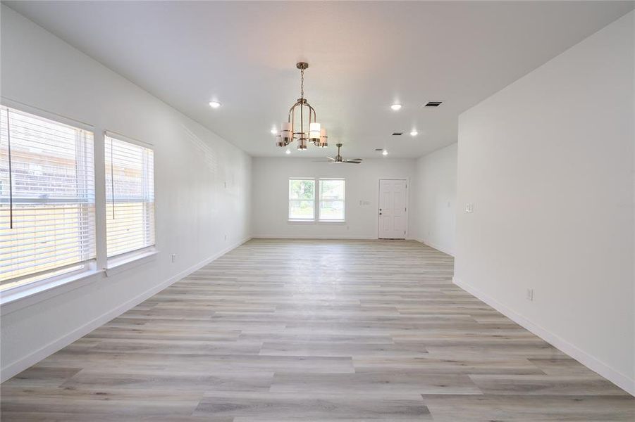 Expansive open-concept living and dining areas featuring light wood-finish flooring, recessed lighting, and a ceiling fan