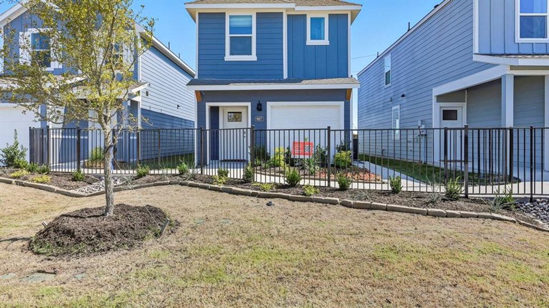 Traditional home with a shingled roof, a fenced front yard, an attached garage, and board and batten siding
