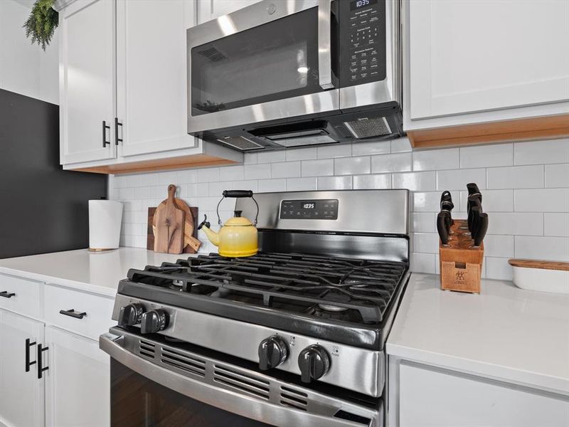 Kitchen featuring tasteful backsplash, white cabinetry, and appliances with stainless steel finishes