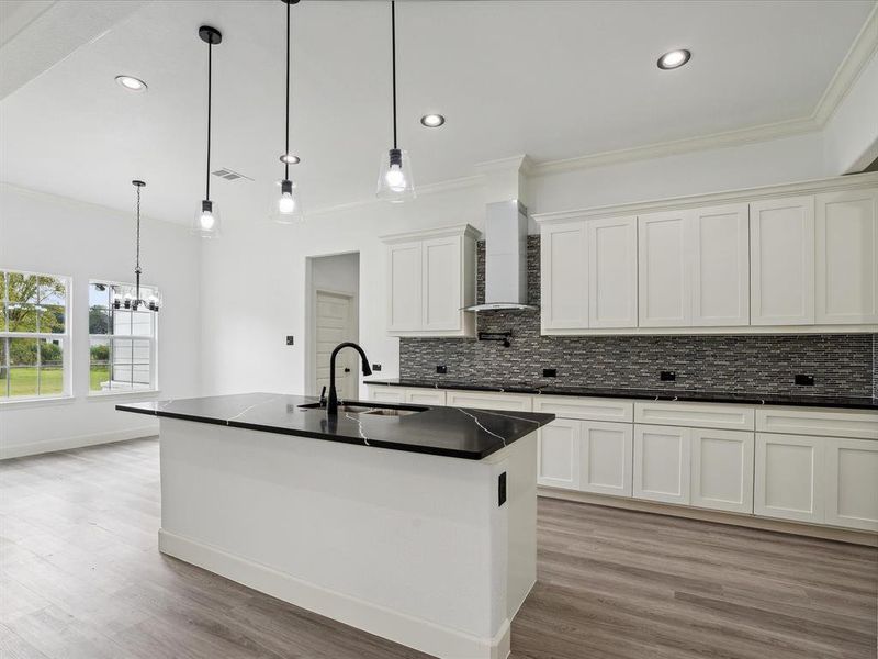 Kitchen featuring light hardwood / wood-style floors, sink, white cabinets, decorative backsplash, and wall chimney range hood