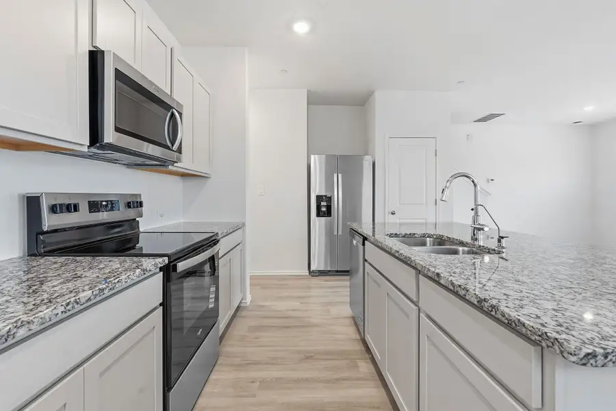 Modern kitchen featuring light cabinetry, stainless steel appliances, speckled stone countertops, a double basin sink, and wood-finish flooring Modern kitchen featuring light cabinetry, stainless steel appliances, speckled stone countertops, a double basin sink, and wood-finish flooring