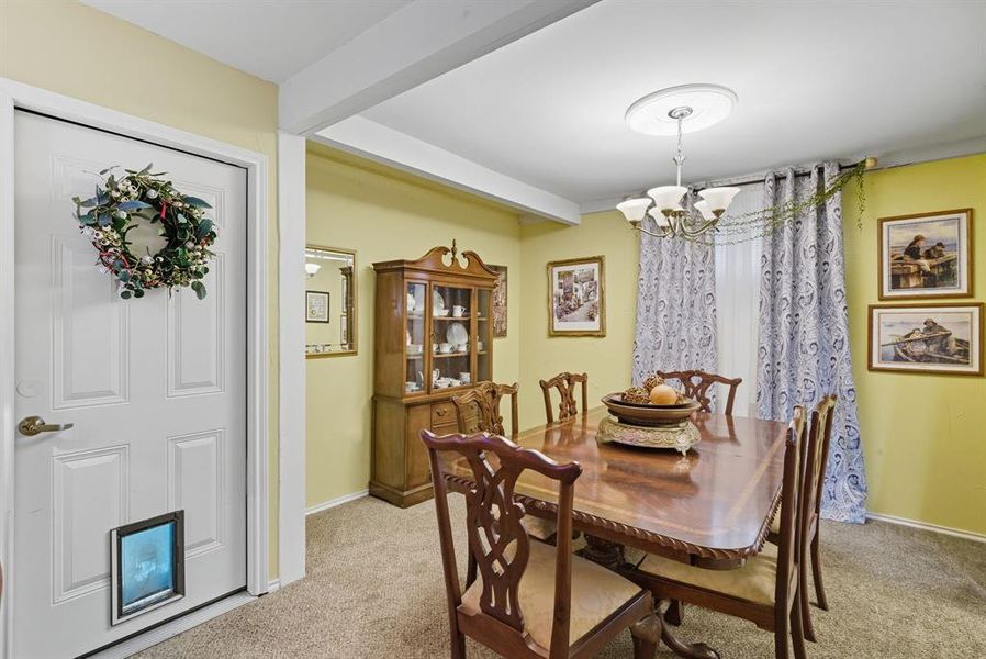 Dining room with a chandelier, light carpet, and beam ceiling Dining room with a chandelier, light carpet, and beam ceiling