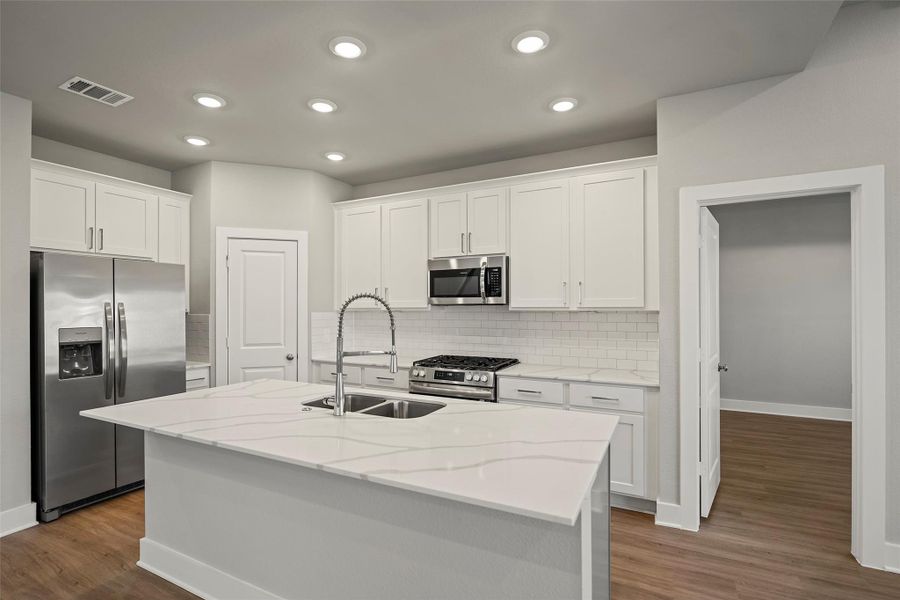 Sleek and functional kitchen with gleaming countertops, abundant cabinetry, and a walk-in pantry.