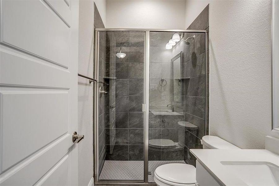 Bathroom featuring vanity, toilet, and a shower with door