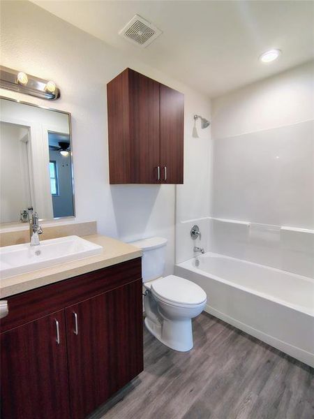 Full bathroom featuring vanity, shower / washtub combination, ceiling fan, wood-type flooring, and toilet