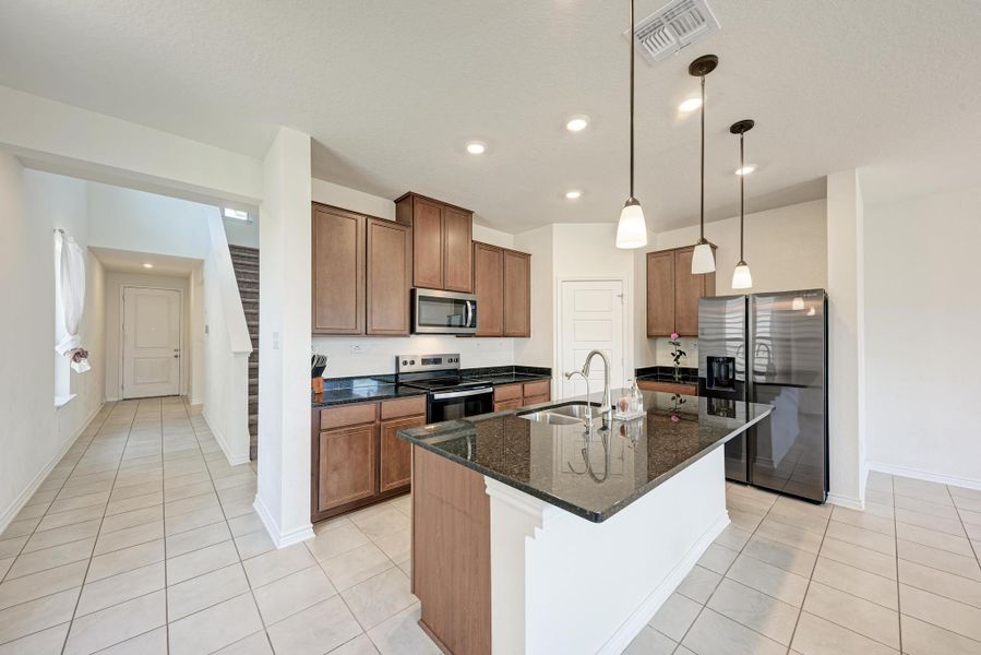 An inviting kitchen features a central island, rich cabinetry, and sleek appliances, perfect for culinary endeavors.