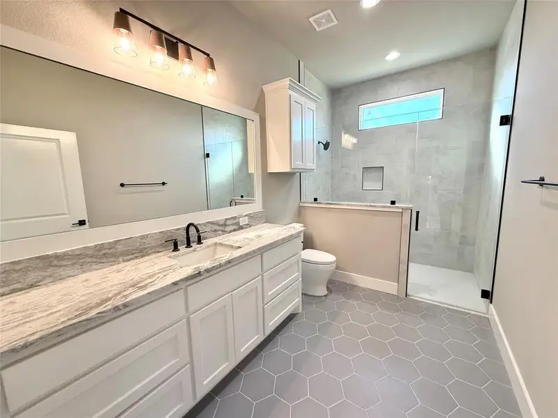 Bathroom with a stall shower, vanity, light tile patterned floors, and recessed lighting Bathroom with a stall shower, vanity, light tile patterned floors, and recessed lighting