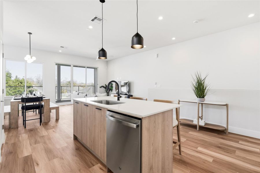 The kitchen island anchors the main level, framed by dual pendant lighting and uninterrupted views into both the dining and living areas. Designed to connect, not divide.
