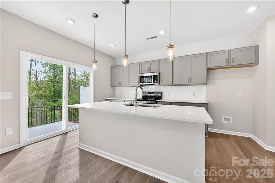 Contemporary tone kitchen with grey cabinetry, chrome hardware, white quartz countertops Contemporary tone kitchen with grey cabinetry, chrome hardware, white quartz countertops