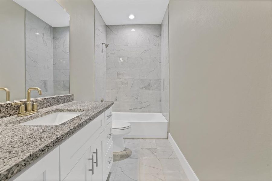 Full bathroom with tiled shower / bath, vanity, and toilet