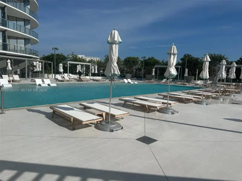 Swimming pool with a zero-entry design, tile decking, and metal-framed shaded pergolas Swimming pool with a zero-entry design, tile decking, and metal-framed shaded pergolas