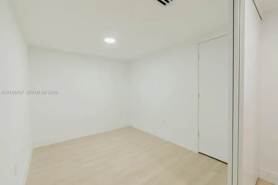Interior space featuring light-toned wood-finish flooring, crisp white walls, recessed ceiling lighting, and a closet with sliding doors Interior space featuring light-toned wood-finish flooring, crisp white walls, recessed ceiling lighting, and a closet with sliding doors
