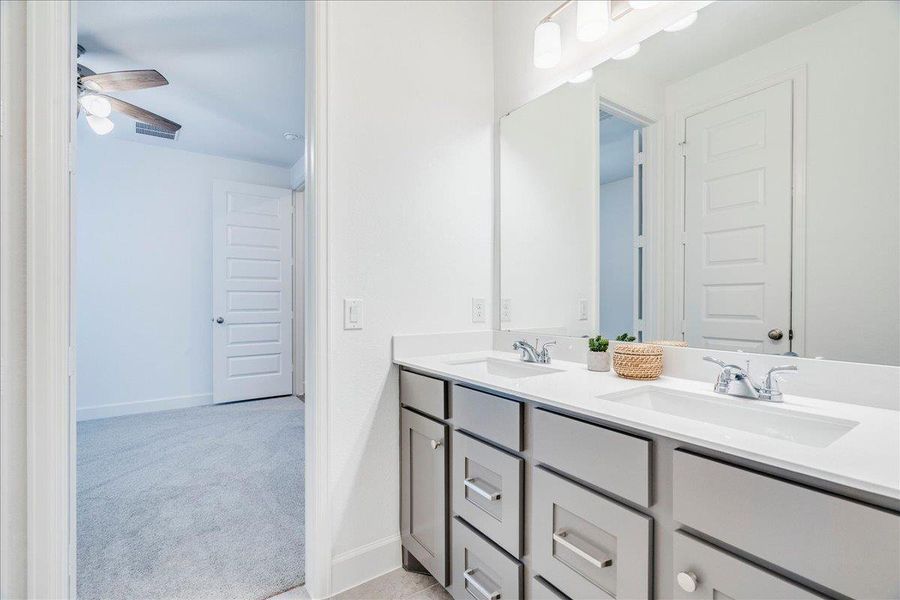 This jack and jill bathroom features a double vanity with two sinks and a large mirror