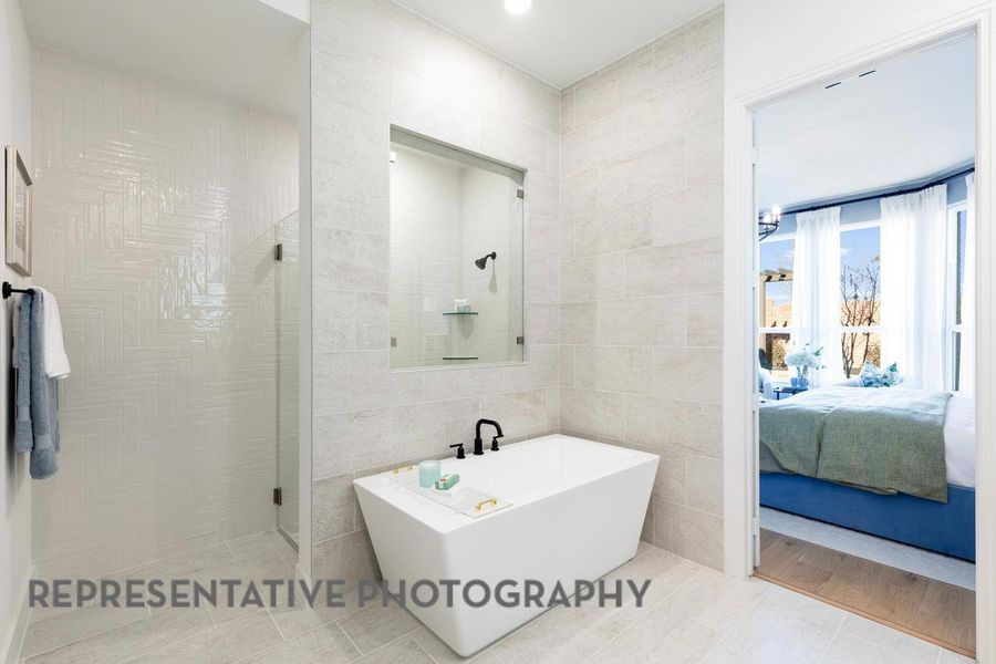 Ensuite bathroom featuring tile walls, a soaking tub, a walk in shower, and tile patterned flooring Ensuite bathroom featuring tile walls, a soaking tub, a walk in shower, and tile patterned flooring