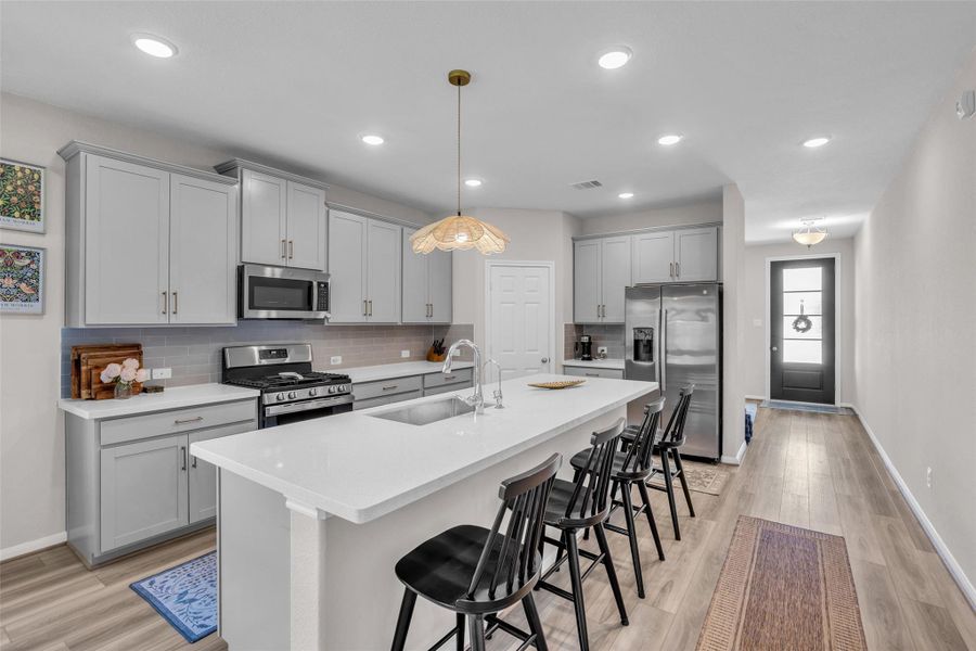 The spacious kitchen island features an integrated sink and doubles as a breakfast bar, providing a convenient spot for casual meals.