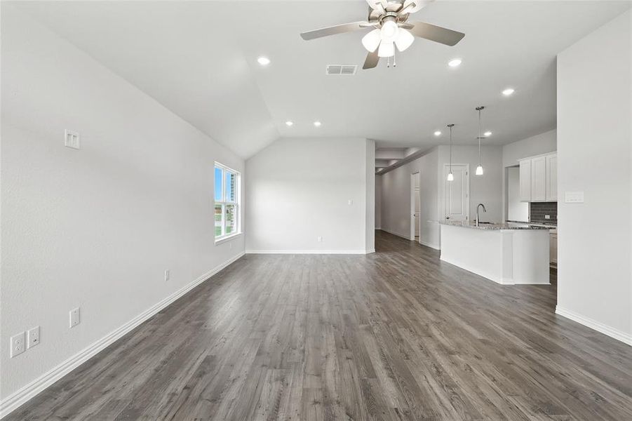 Unfurnished living room featuring lofted ceiling, recessed lighting, dark wood-type flooring, and ceiling fan